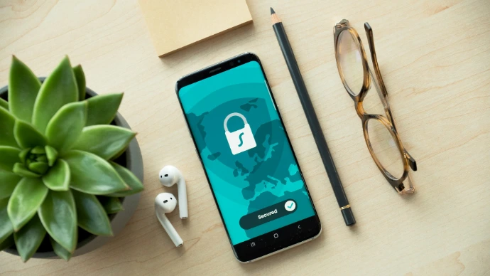 A smartphone displaying a security lock icon on a wooden desk with a succulent